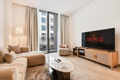 a living room with a couch and a tv at Elegant 1BR with Pool, Gym Access and Kid's Play Area in Dubai