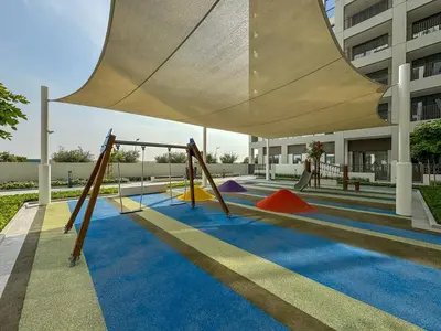 a playground with colorful swings on a blue carpet at Elegant 1BR with Pool, Gym Access and Kid's Play Area in Dubai