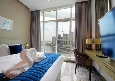 a person is laying on a bed in a hotel room at Burj Khalifa & Canal View LuxeStudio in DAMACPrive in Dubai