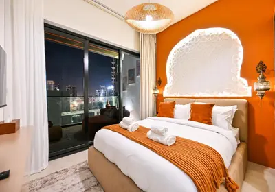 a bedroom with a large bed with an orange wall at Luxurious One Bed Near Dubai Mall with Burj and Canal View in Dubai