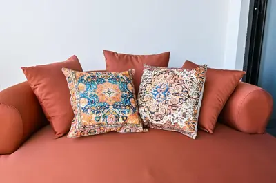 a orange couch with four pillows on it at Luxurious One Bed Near Dubai Mall with Burj and Canal View in Dubai