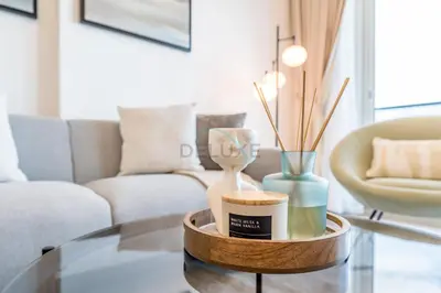 a living room with a table with vases and a couch at Near Dubai Miracle Garden 1BR with Private Balcony, Orchid Residence, Al Barsha South by Deluxe Holiday Homes in Dubai