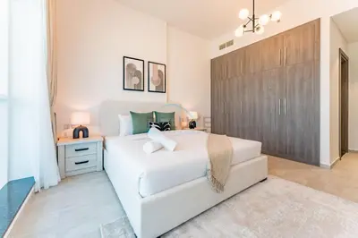 a bedroom with a white bed and a wooden closet at Near Dubai Miracle Garden 1BR with Private Balcony, Orchid Residence, Al Barsha South by Deluxe Holiday Homes in Dubai