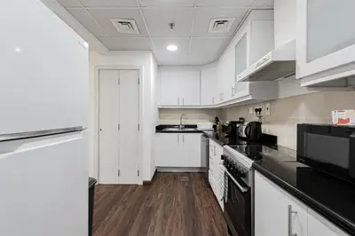 a kitchen with white cabinets and black appliances at Short Stay Apartment Shams 1 Jumeirah Beach Residence 2 Bed Sleeps 6 - DVH HOLIDAY HOMES in Dubai