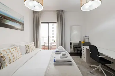 a white room with a large bed and a desk at Short Stay Apartment Shams 1 Jumeirah Beach Residence 2 Bed Sleeps 6 - DVH HOLIDAY HOMES in Dubai