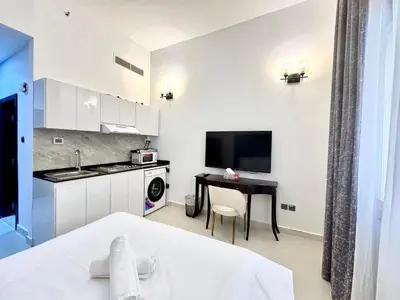 a room with a bed and a kitchen with a table at Al Manara Classic Deluxe Studio in Dubai