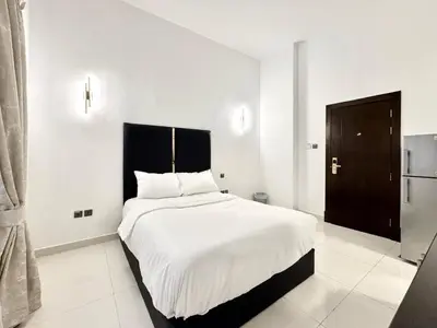 a white bedroom with a large bed with white sheets at Al Manara Classic Executive Studio in Dubai