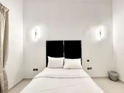 a bedroom with a bed with white sheets and a black headboard at Al Manara Classic Executive Studio in Dubai