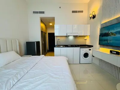 a bedroom with a bed and a kitchen with a washing machine at Al Manara Premium Deluxe Sheikh Zayed View Studio in Dubai