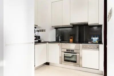 a kitchen with white cabinets and stainless steel appliances at JW Marriott Marina By Luxe Living Collection - Wane By Somiya Infinity Pool in Dubai