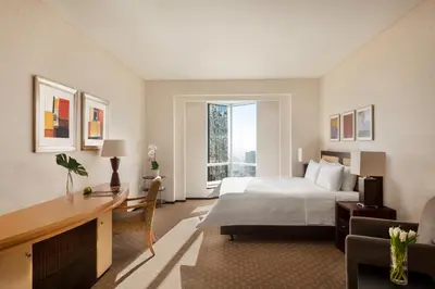 a hotel room with a bed and a desk and a window at Shangri-La Apartments in Dubai