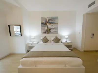 a white bedroom with a large bed and two tables at Appartement Moderne Dubai Marina in Dubai