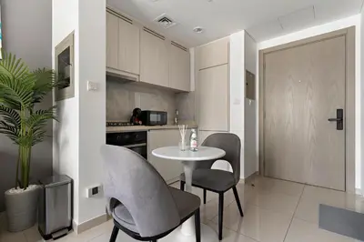 a kitchen with a table and chairs in a kitchen at Stylish 1BR In Zada Tower With Pool Views in Dubai