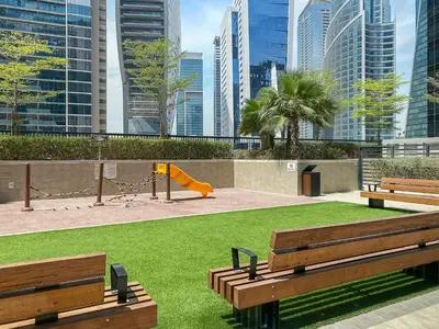 two wooden benches in a park with a playground at Stylish 1BR In Zada Tower With Pool Views in Dubai