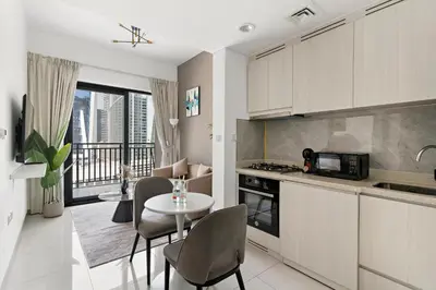 a kitchen with a table and chairs and a dining room at Stylish 1BR In Zada Tower With Pool Views in Dubai