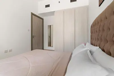 a white bedroom with two beds and a headboard at Stylish 1BR In Zada Tower With Pool Views in Dubai