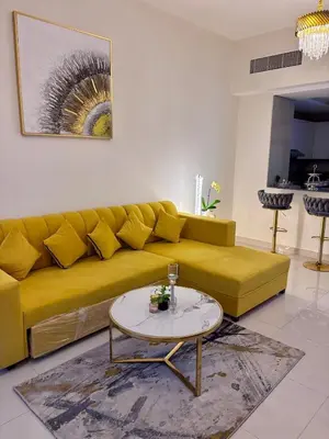 a yellow couch in a living room with a table at Burj Views 2 BHK Apartment in Dubai