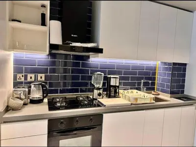 a kitchen with white cabinets and blue tiles on the wall at Mag 318 - 3 min walk to Dubai Mall - Luxury Studio - Pool & SLS View in Dubai