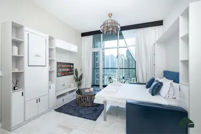 a bedroom with a white bed and a large window at Cozy Studio with City Views at Bayz by Danube by BMS in Dubai