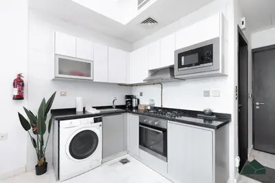 a white kitchen with a washing machine and a washer at Cozy Studio with City Views at Bayz by Danube by BMS in Dubai