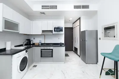 a kitchen with white cabinets and a washer and dryer at Cozy Studio with City Views at Bayz by Danube by BMS in Dubai