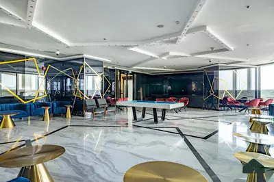 a room with a ping pong table and chairs at Cozy Studio with City Views at Bayz by Danube by BMS in Dubai