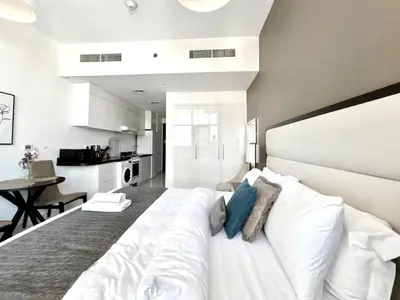 a bedroom with a large white bed with blue pillows at Homes2Retreat - Chic & Cozy Studio in Damac in Dubai
