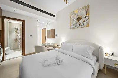 a bedroom with a white bed and a bathroom at FIRST CLASS Studio Touch of Luxury & Comfort in Dubai