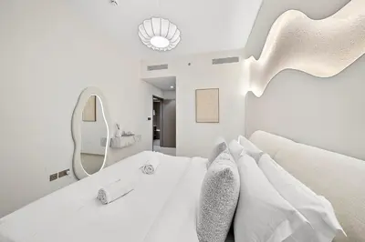 a white bedroom with a large bed and a mirror at FIRST CLASS 2BR Burj Khalifa & Fountain view in Dubai