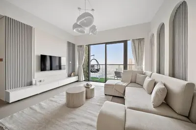 a white living room with a couch and a tv at FIRST CLASS 2BR Burj Khalifa & Fountain view in Dubai