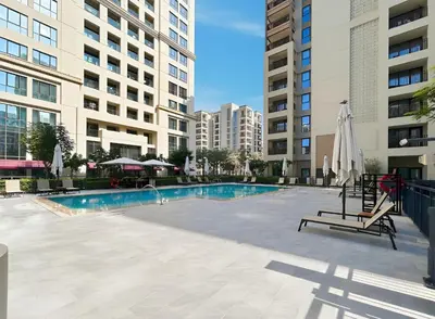 a swimming pool with chairs and umbrellas and buildings at 1BR Summer 4 Direct Beach Access in Dubai