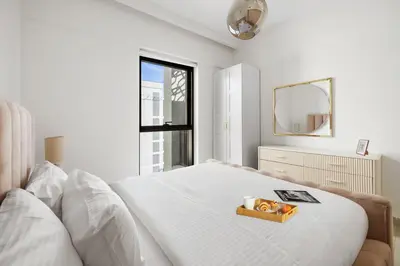 a white bedroom with a bed with a tray on it at 1BR Summer 4 Direct Beach Access in Dubai