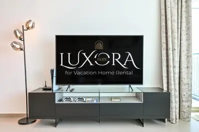 a living room with a tv on a dresser at Burj Khalifa View, Luxury Two-Bedroom Residence, PlayStation 5, Swimming Pool and Fitness Center in Dubai