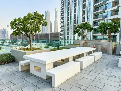a white table and benches on a patio with buildings at Burj Khalifa View, Luxury Two-Bedroom Residence, PlayStation 5, Swimming Pool and Fitness Center in Dubai