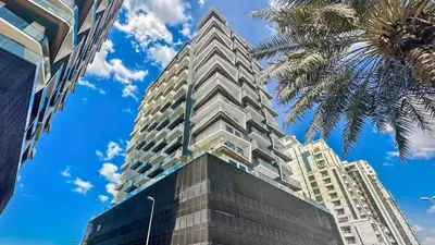 a tall building with a palm tree in front of it at TRPS - Binghatti Nova, Jumeirah Village Circle - Premium 1BR with Great Amenities in Dubai