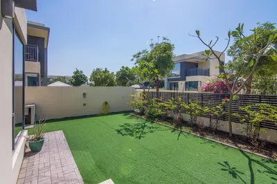 a backyard with a green lawn in front of a building at Elegant 4 bedrooms plus maid Villa in the Heart of Dubai Hills in Dubai