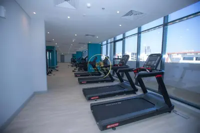 a row of treadmills in a gym with windows at 3BHK Apartment located in Azizi riviera 34 in Dubai