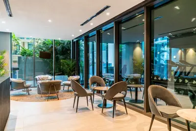 a restaurant with chairs and tables and windows at Escape24 Cozy Studio with Pool View in JVC in Dubai