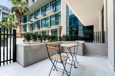 a table and chairs in front of a building at Escape24 Cozy Studio with Pool View in JVC in Dubai