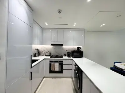a white kitchen with white cabinets and a stove at Spacious Luxury 1br Jvc Balcony & Pool in Dubai
