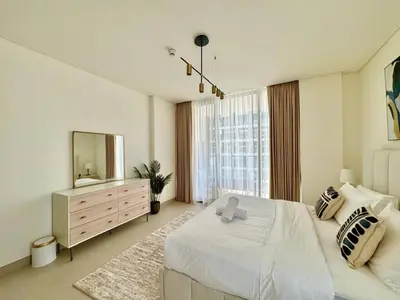 a white bedroom with a large bed and a mirror at Spacious Luxury 1br Jvc Balcony & Pool in Dubai
