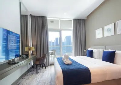 a hotel room with a bed and a desk and a window at Elegant Studio with Canal Views DAMAC Prive in Dubai