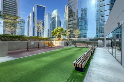 a green lawn in a building with benches and buildings at City Views 1BR with Balcony Near Dubai Water Canal, Zada Tower, Business Bay by Deluxe Holiday Homes in Dubai