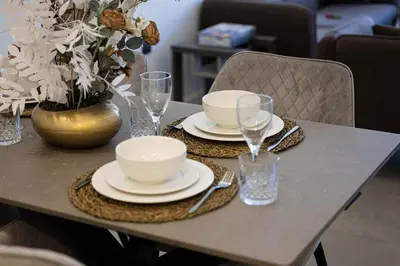 a table with plates and glasses and a vase with flowers at Daniels 2BR at Jumeirah Garden City in Dubai