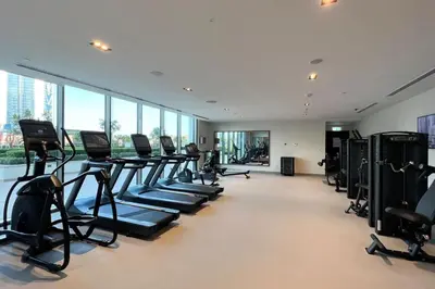 a gym with rows of treadmills and exercise bikes at Mahogany 7 - 2BR 6PAX - Walk to Burj & Dubai Mall in Dubai