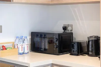 a microwave on a counter with bottles of water at Mahogany 5 - 2BR 6PAX - Infinity Pool & High-floor in Dubai