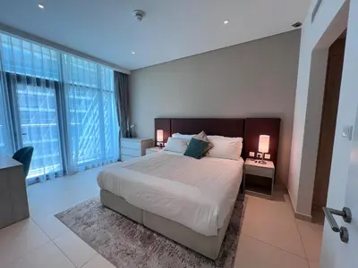 a bedroom with a large bed with two lamps and windows at Stunning 1 bedroom apartment in Seven Palm Dubai in Dubai