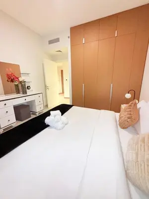 a bedroom with a large white bed with towels on it at 1 Bed With Private Beach Access In Dubai Creek Harbour in Dubai
