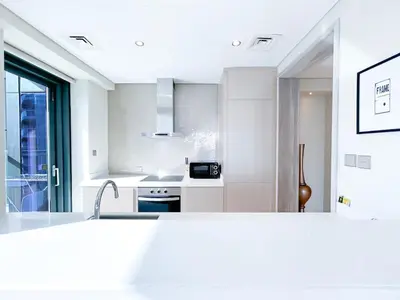a white kitchen with a sink and a counter at 2BR Apartment in Paramount Tower in Dubai