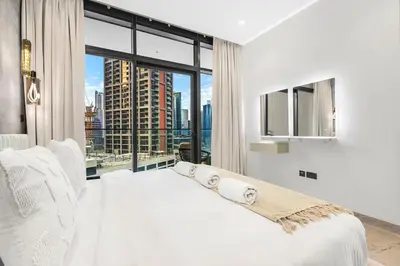 a bedroom with a white bed and a large window at Luxury 1BR in Downtown Dubai with Burj Khalifa Views, Pool, Gym & Free Parking in Dubai